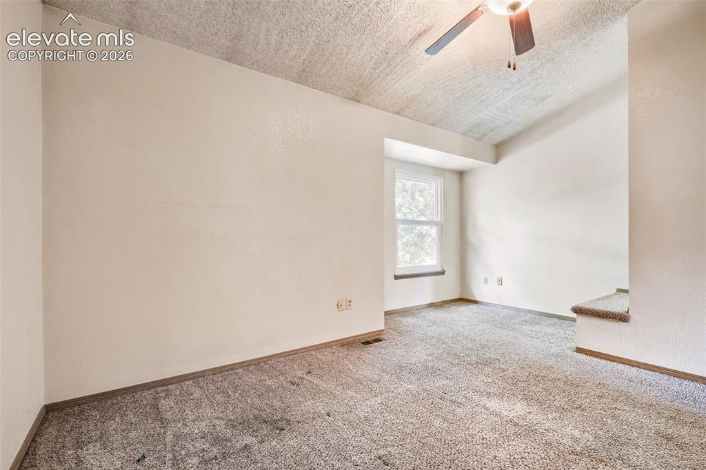 Image 14 of 35: Carpeted room with a ceiling fan, textured ceiling, and a window providing