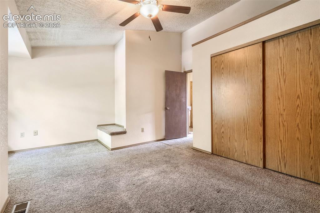Image 17 of 35: Carpeted room featuring a ceiling fan with light fixture, wood-finish slidi
