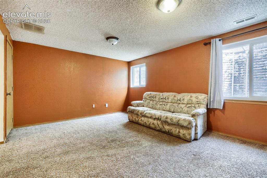 Image 23 of 35: Carpeted room featuring warm orange walls and a textured ceiling