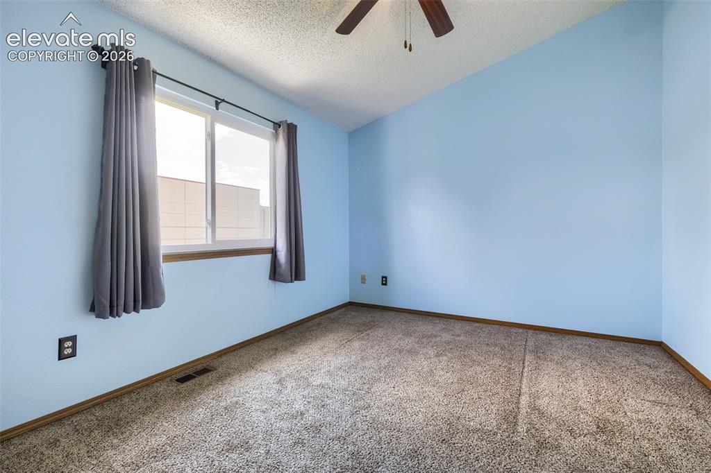 Image 26 of 35: Bright room featuring a window with wood trim, textured ceiling, and a ceil
