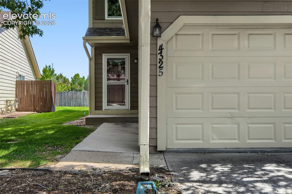 Image 3 of 35: Attached garage featuring panel doors and house numbers