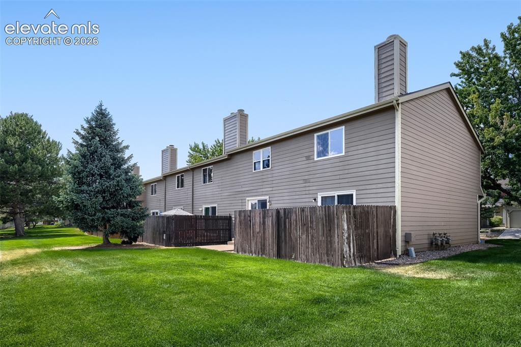 Image 32 of 35: Rear exterior of the property featuring a private patio area with a wood fe