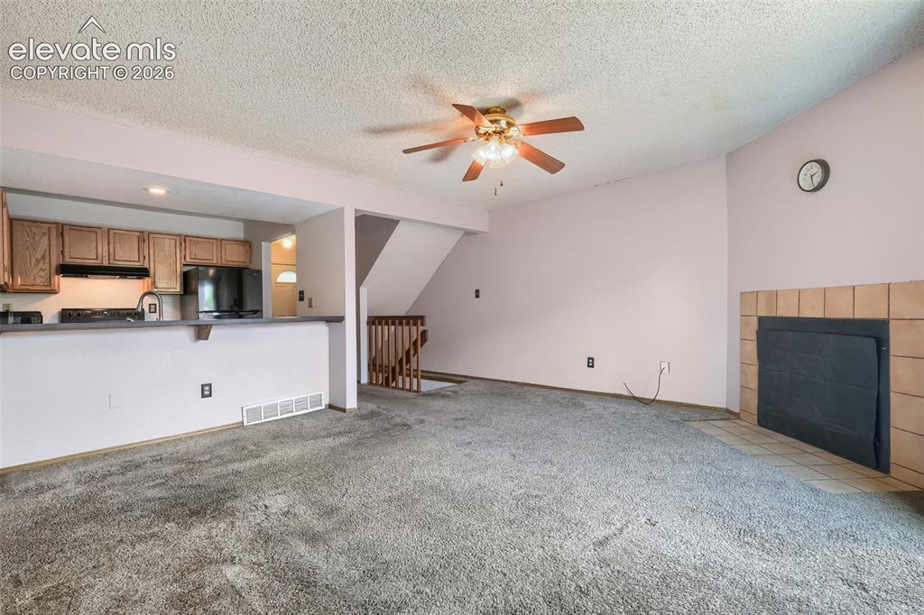 Image 9 of 35: Living area featuring a ceiling fan, fireplace with a tiled surround, and c