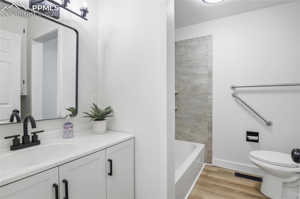 Image 12 of 44: The bathroom features a modern vanity with a white countertop and dark fixt