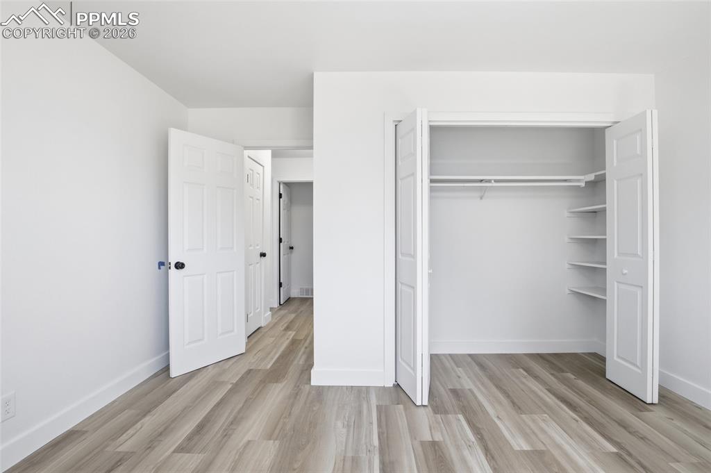 Image 14 of 44: This room features light-toned flooring, white walls, and a closet with bif