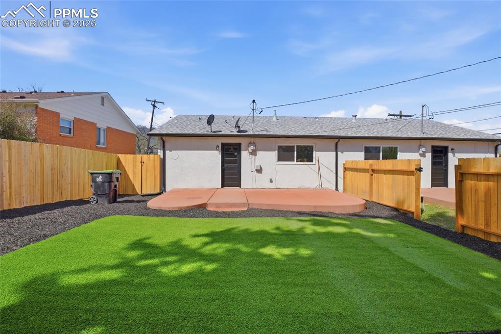 Image 15 of 44: The property features a private backyard with artificial turf, a paved pati