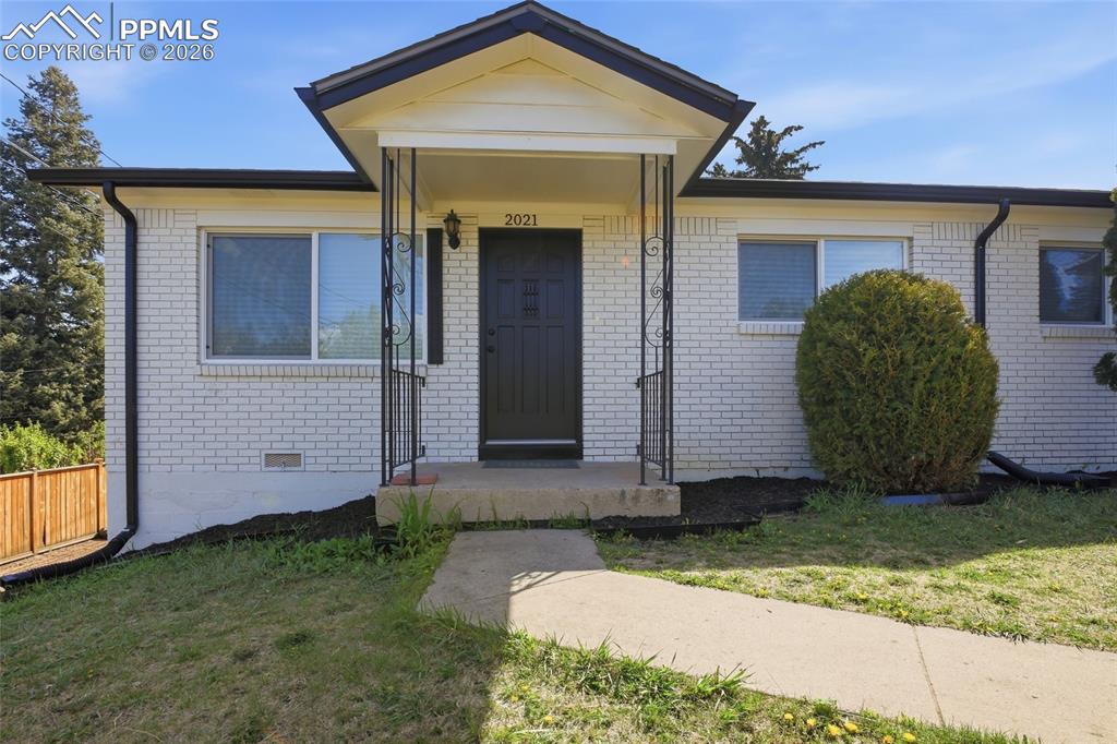 Image 17 of 44: The property features a white brick exterior with a dark front door and a c