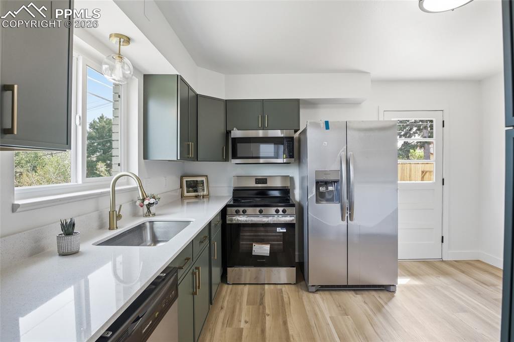 Image 22 of 44: The kitchen features sleek dark cabinetry with gold-toned hardware, white c