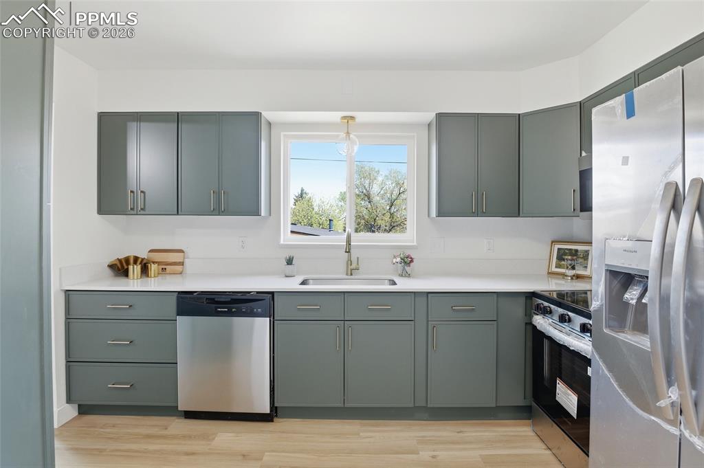 Image 23 of 44: The kitchen features light green cabinetry with brushed nickel hardware, a 