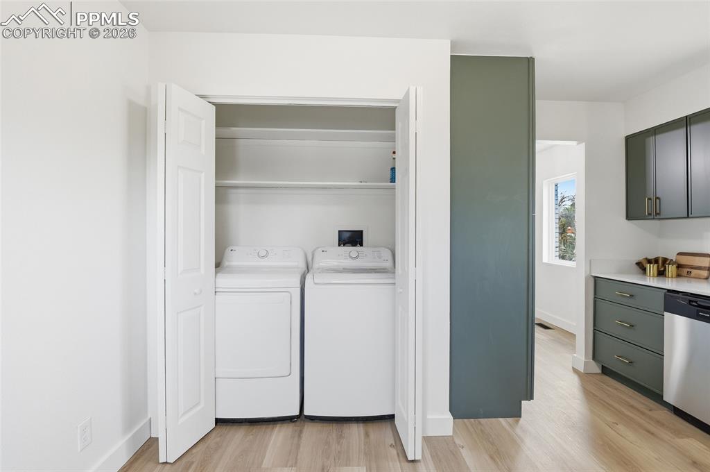 Image 25 of 44: Laundry area featuring a washer and dryer, bi-fold doors, and integrated sh