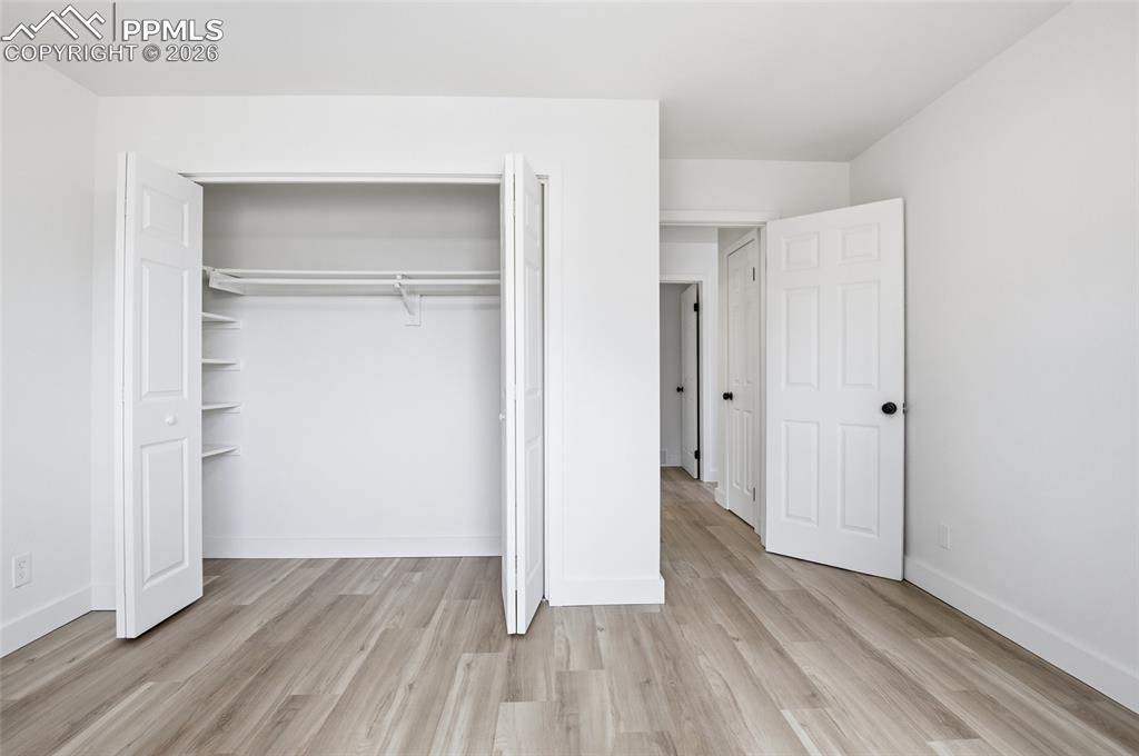Image 30 of 44: This room features light-toned wood flooring, white walls, and a closet wit