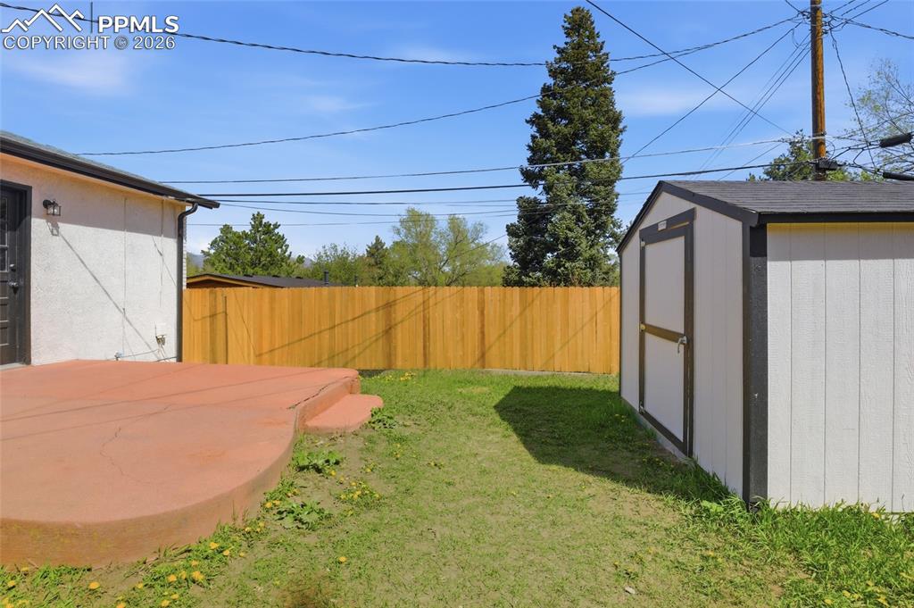 Image 33 of 44: The property features a private yard with a wooden fence and a storage shed