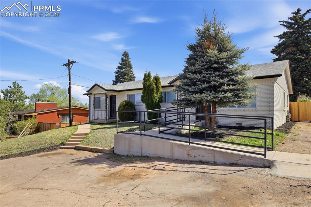 Image 38 of 44: The property features a light-colored exterior, a grey roof, and a front en