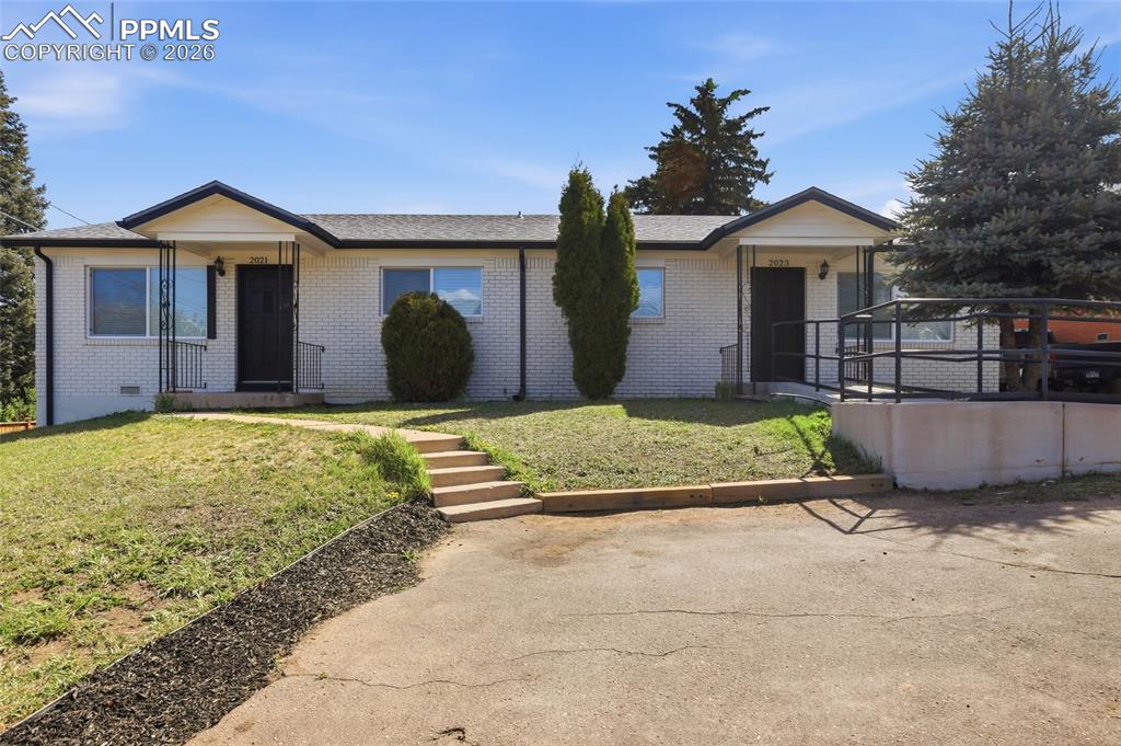 Image 39 of 44: The property features a light-colored brick exterior with dark trim and a d