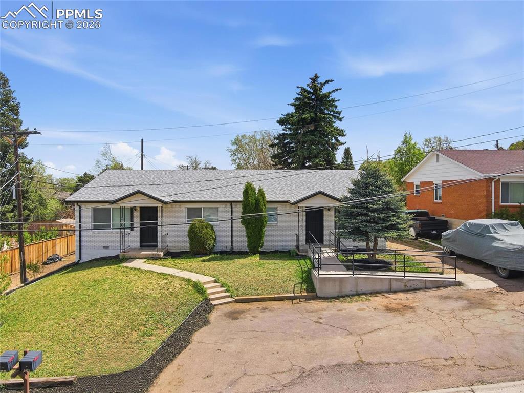Image 41 of 44: The property features a light-colored exterior, a grey roof, and a front ya