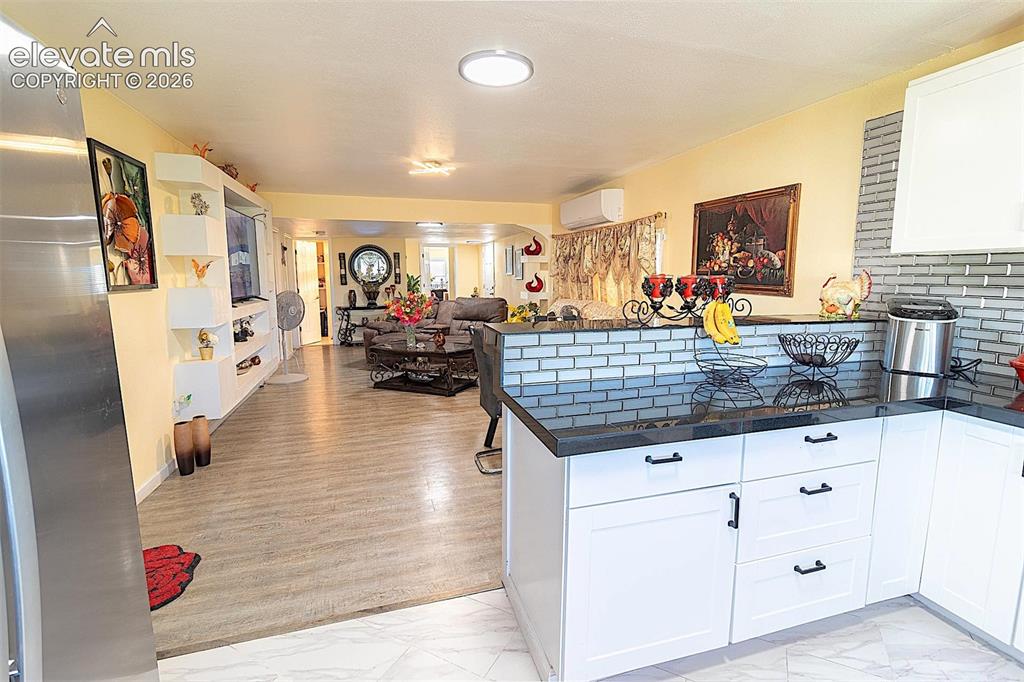 Image 22 of 25: Kitchen featuring light marble finish floors, a peninsula, dark countertops
