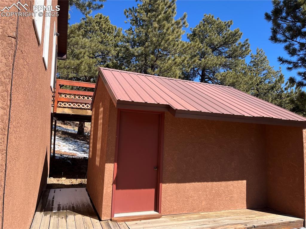Image 6 of 28: East side of the building with deck. A large storage area. Home has a me