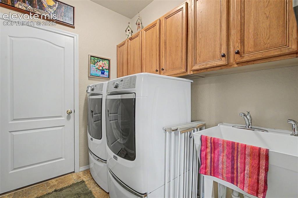 Image 14 of 31: Laundry features storage cabinets, a utility sink and access to the garage.