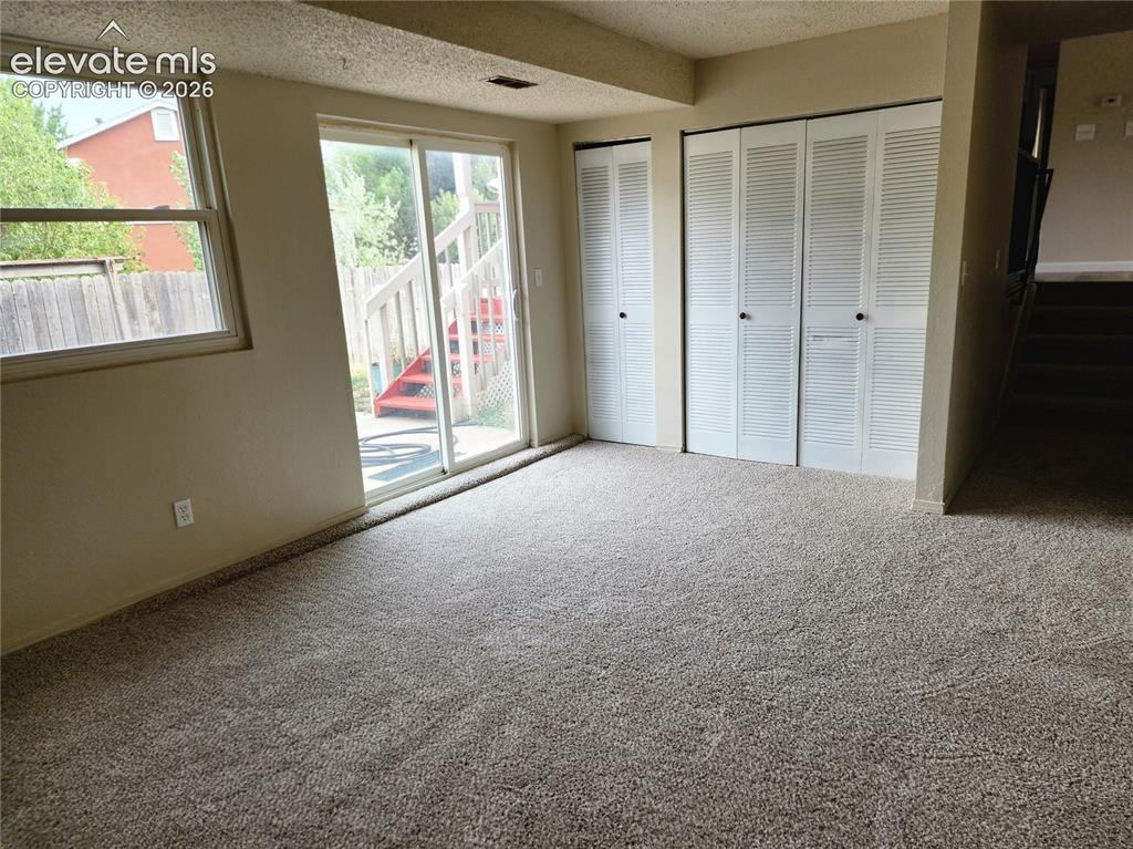 Image 11 of 17: Carpeted room featuring a double-pane window, sliding glass door, and two s