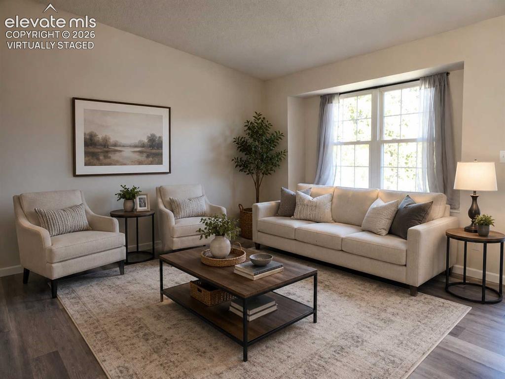 Image 2 of 17: Living area featuring neutral wall tones, a large bay window, wood-finish f