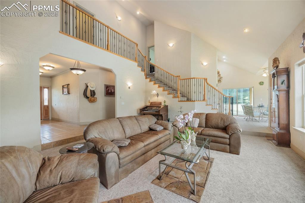 Image 16 of 41: Living area with high vaulted ceiling, stairs, arched walkways, and recesse