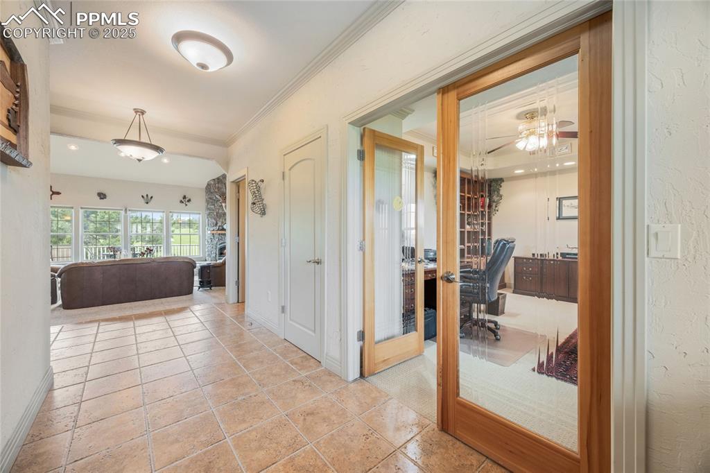 Image 18 of 41: Hall with ornamental molding, a textured wall, an office area, and french d