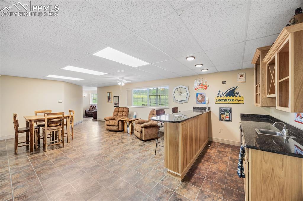 Image 21 of 41: Kitchen with a drop ceiling, a breakfast bar, dark stone countertops, a pen