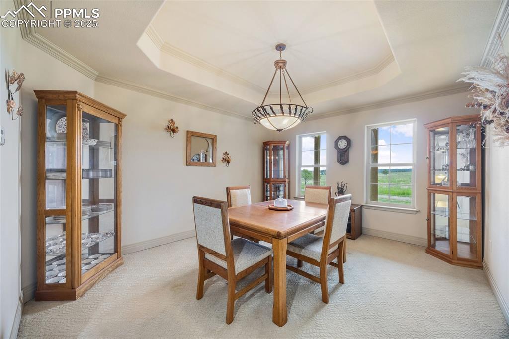 Image 25 of 41: Dining space featuring light colored carpet, crown molding, and a raised ce