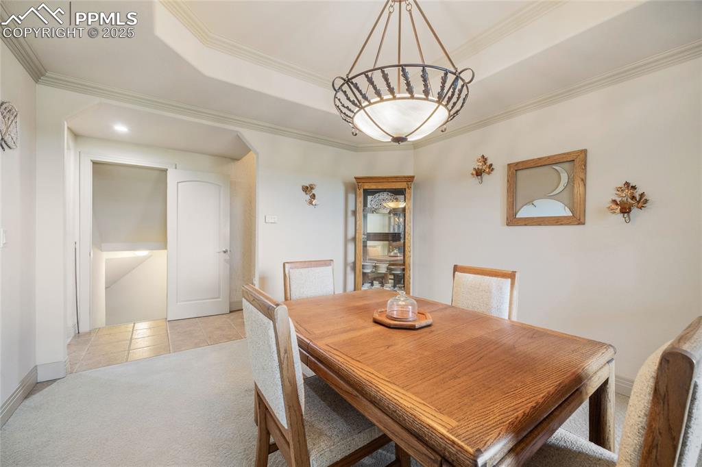 Image 26 of 41: Dining space with a tray ceiling, light carpet, light tile patterned floori