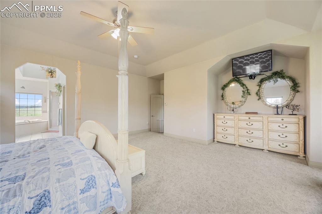 Image 29 of 41: Bedroom with light carpet, ensuite bathroom, and ceiling fan