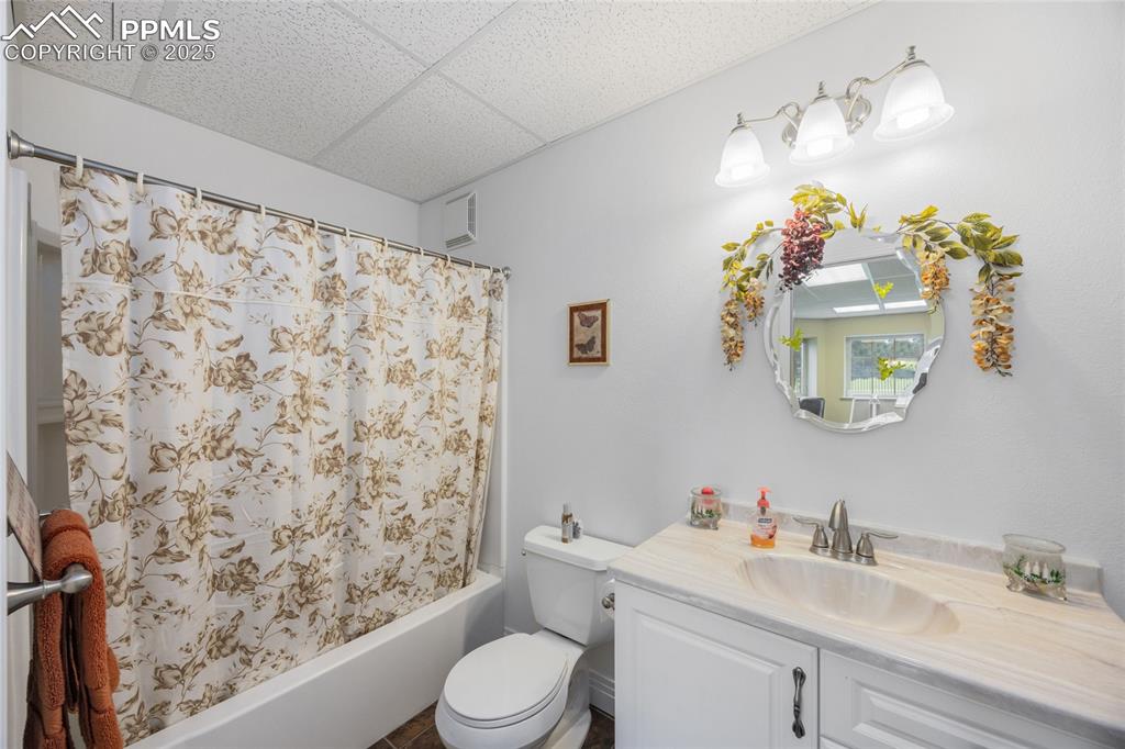 Image 32 of 41: Bathroom with vanity, shower / bathtub combination with curtain, and a drop