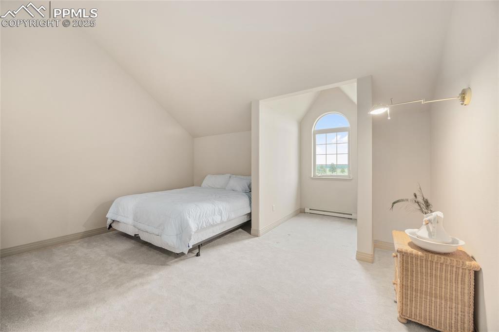 Image 36 of 41: Bedroom featuring lofted ceiling, a baseboard radiator, and light carpet