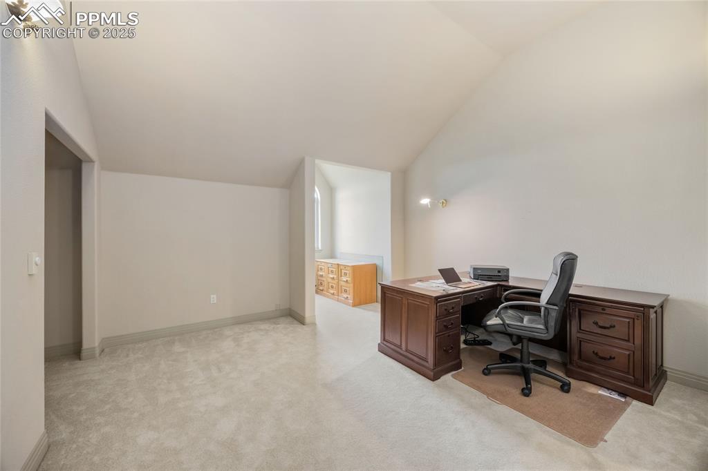 Image 37 of 41: Office space with vaulted ceiling and light colored carpet