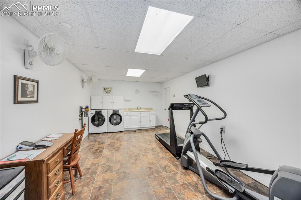 Image 38 of 41: Exercise area with a drop ceiling and washing machine and dryer
