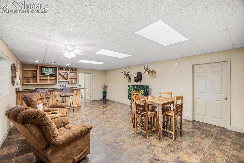 Image 39 of 41: Dining space with bar area, a paneled ceiling, and a ceiling fan