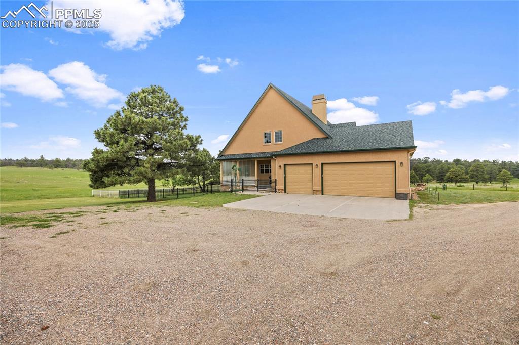 Image 4 of 41: View of property exterior featuring driveway, a chimney, a garage, stucco s