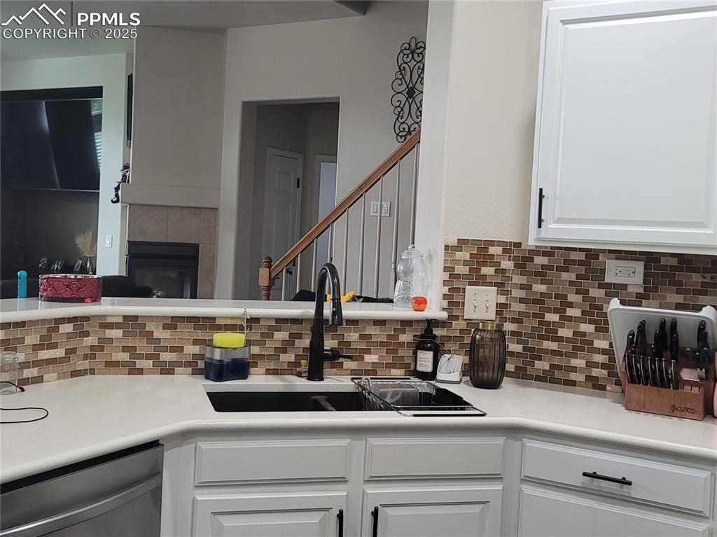 Image 10 of 11: Kitchen featuring white cabinets, light countertops, tasteful backsplash, s