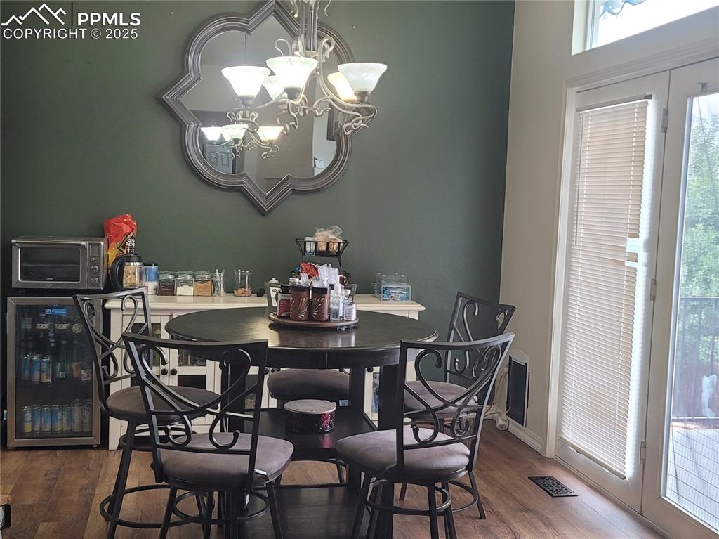 Image 11 of 11: Dining area with dark wood-style floors, wine cooler, and a chandelier