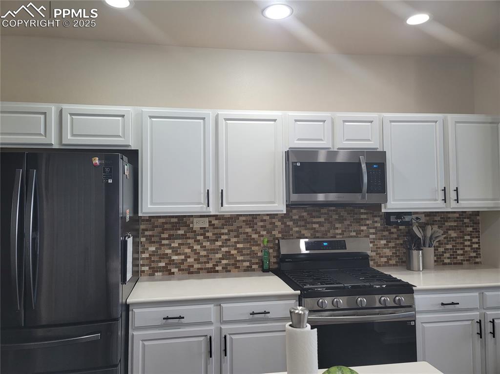 Image 6 of 11: Kitchen featuring appliances with stainless steel finishes, light counterto