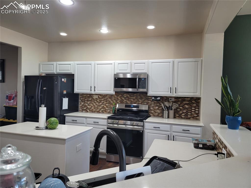 Image 7 of 11: Kitchen featuring stainless steel appliances, tasteful backsplash, white ca