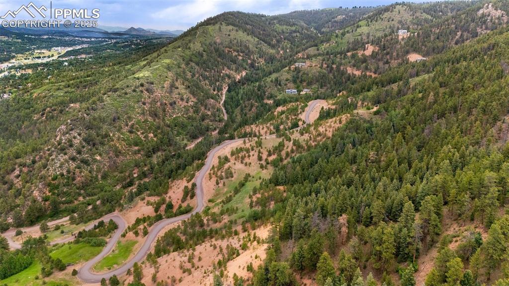 Image 19 of 21: Aerial view of property and surrounding area with mountains and a heavily w