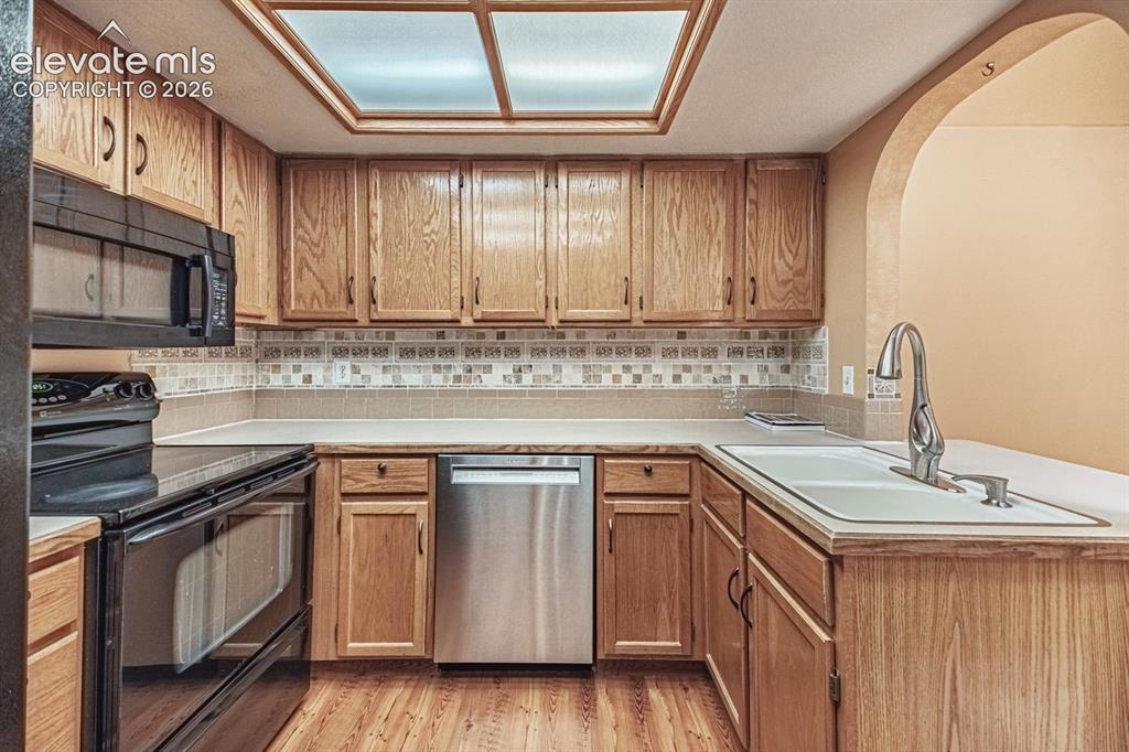 Image 12 of 36: Kitchen featuring wood cabinetry, light-toned countertops, a mosaic tile ba