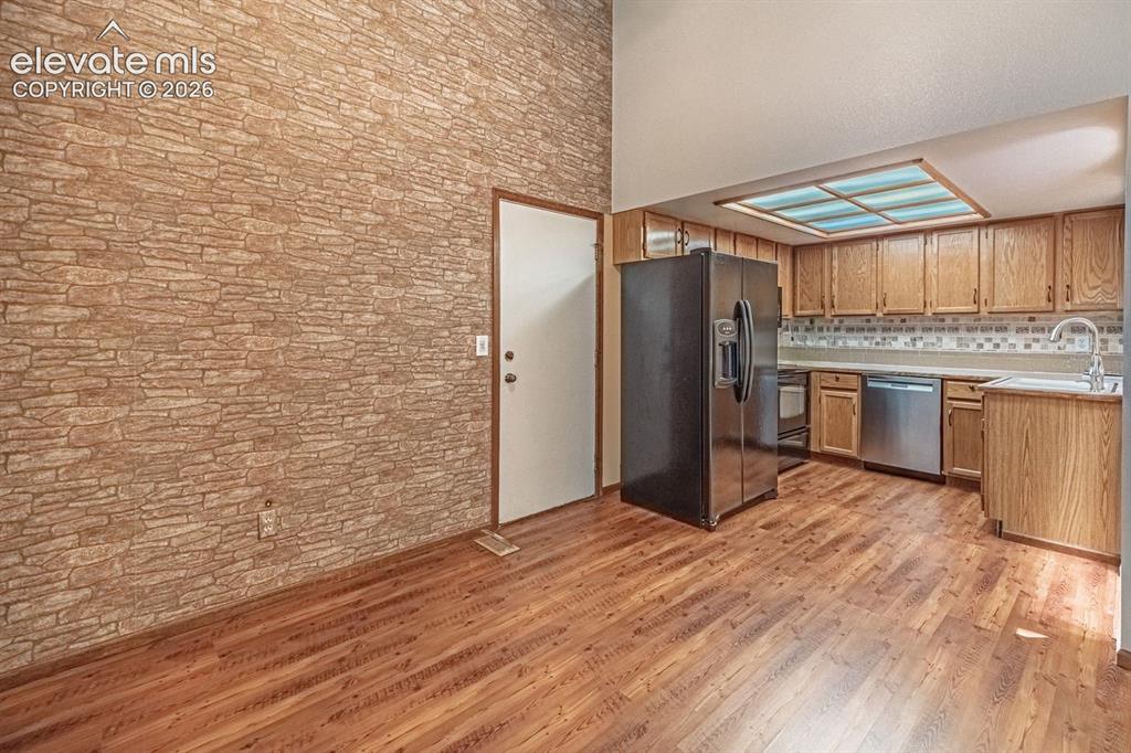 Image 13 of 36: Kitchen space featuring wood-finish flooring, oak cabinetry, stainless stee