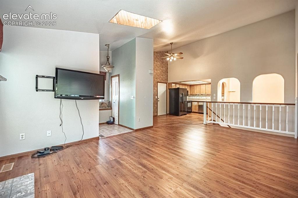 Image 14 of 36: Vaulted ceilings featuring a skylight, wood-finish flooring, and a white ba