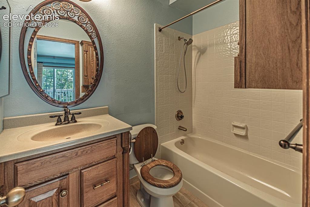 Image 17 of 36: Bathroom featuring a wood-finish vanity with an integrated sink and an orna