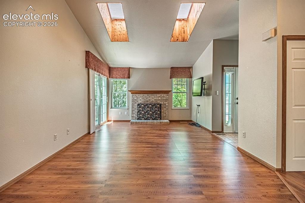Image 20 of 36: Vaulted ceiling living area featuring wood-finish flooring and two rectangu
