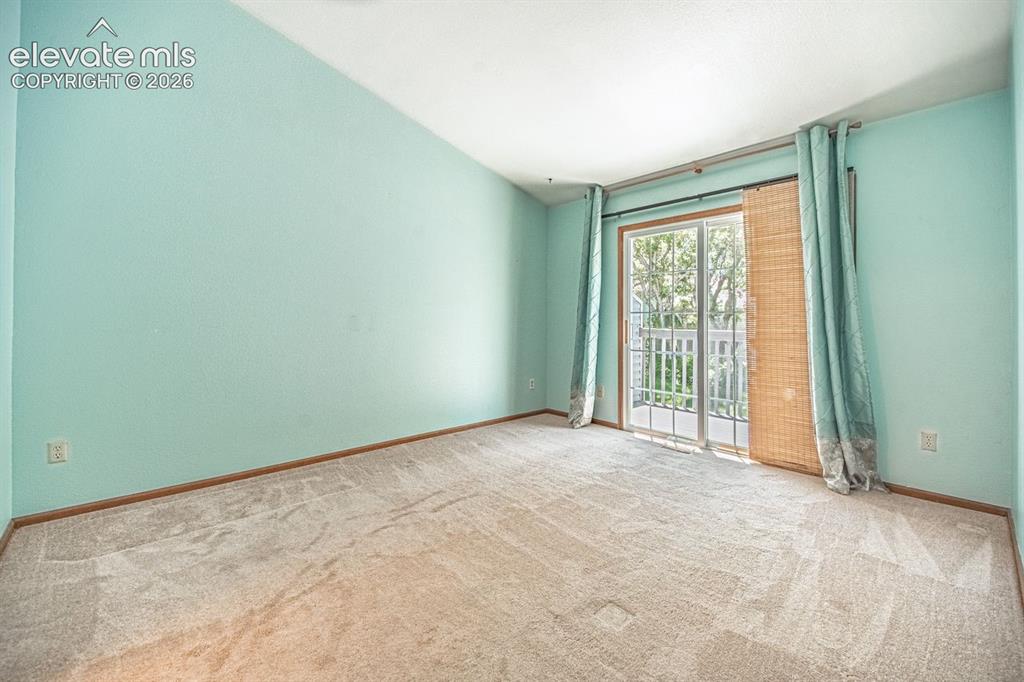 Image 21 of 36: Carpeted room featuring a vaulted ceiling and a sliding glass door