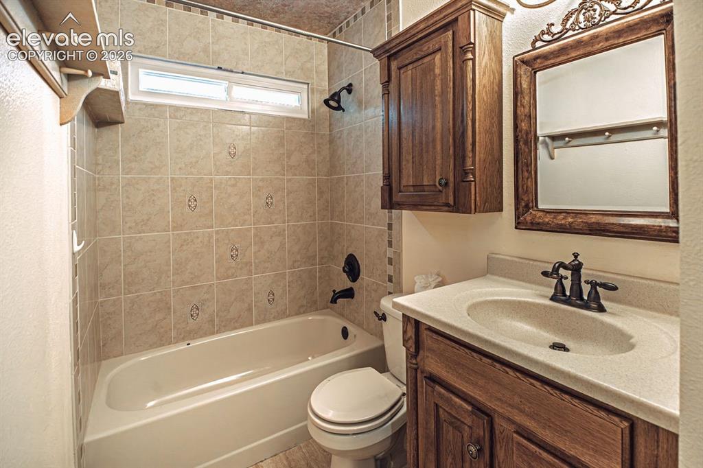 Image 25 of 36: Bathroom featuring a light-toned tile shower surround with decorative accen