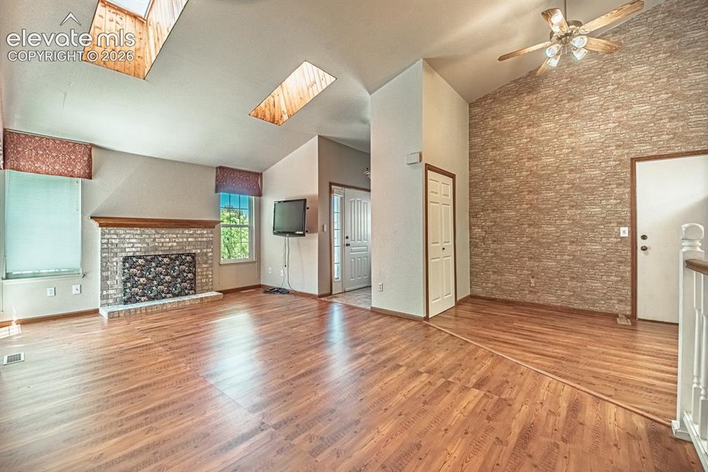 Image 5 of 36: Spacious living area featuring wood-finish flooring, vaulted ceilings with
