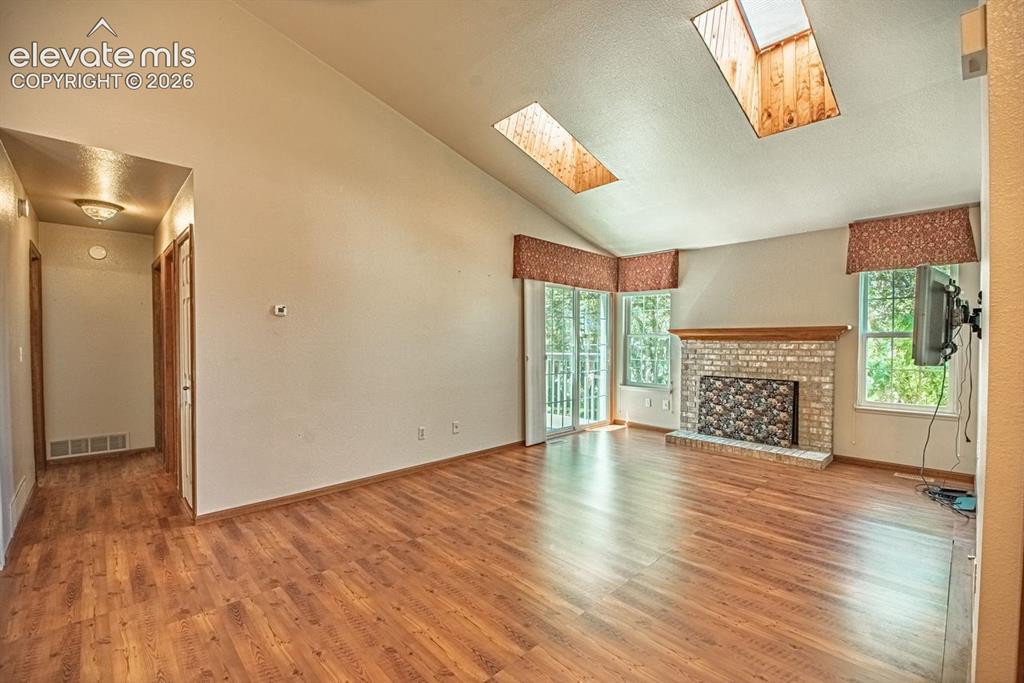 Image 6 of 36: Spacious living area featuring a vaulted ceiling with two skylights, a bric